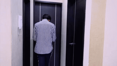 Man In Striped Shirt Standing In Front Of Black Door GIF
