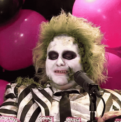 Man In Striped Shirt Talking Into Microphone With Pink Balloons GIF