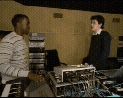 Man In Striped Shirt Talking To Another Man In Dark Room GIF