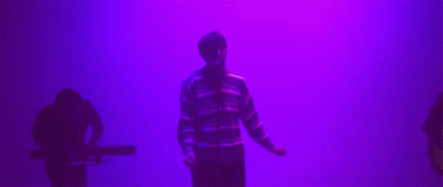 Man In Striped Sweater In Front Of Purple Wall GIF