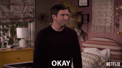 Man In Striped Sweater Saying Okay In Bedroom GIF