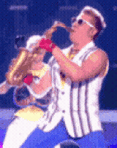 Man In Striped Vest Playing Saxophone On Stage GIF
