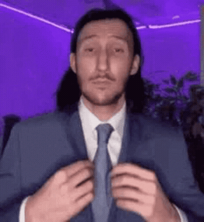 Man In Suit Adjusting Tie In Purple Room GIF