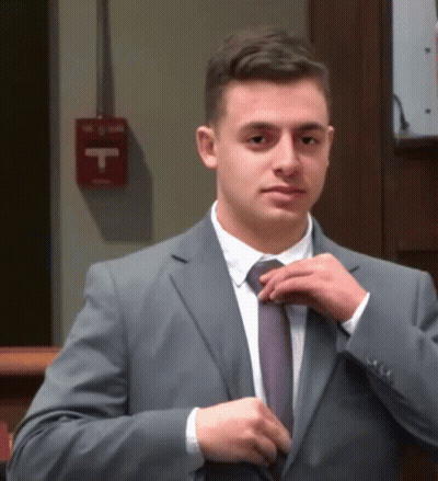 Man In Suit Adjusts Tie By Fire Extinguisher GIF