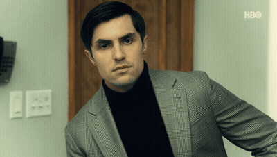 Man In Suit And Black Turtleneck In Front Of HBO Wall GIF