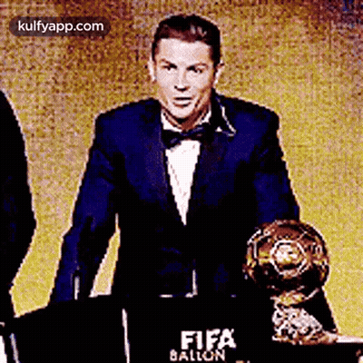 Man In Suit And Bow Tie Holding Trophy At Podium GIF