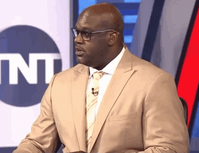 Man In Suit And Bow Tie Sitting In Front Of SNL Sign GIF