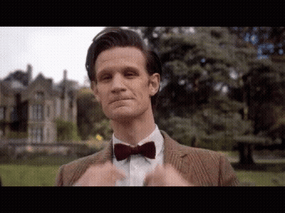 Man In Suit And Bow Tie Standing In Front Of Building GIF