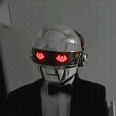 Man In Suit And Bow Tie With Red-Eyed Robot Helmet GIF