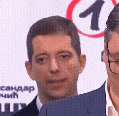 Man In Suit And Glasses Looking At Camera GIF