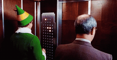 Man In Suit And Green Hat Elf In Elevator GIF