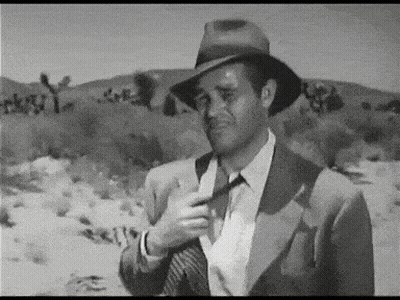 Man in Suit and Hat Adjusting Tie in Desert