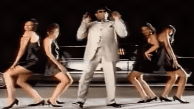 Man In Suit And Hat Dancing With Three Women In Black Dresses In Front Of A Car GIF