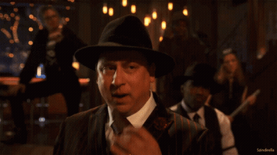 Man In Suit And Hat In Front Of Sandroella Sign GIF