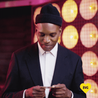 Man In Suit And Hat Looking At Phone With Yellow Heart Saying BG GIF