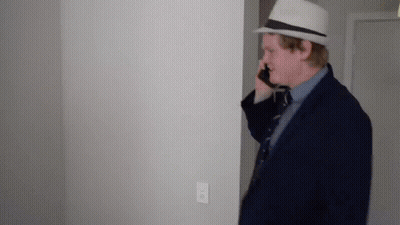 Man In Suit And Hat Talking On Cell Phone In Hallway GIF