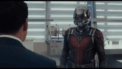 Man In Suit And Helmet Talking To Superhero GIF