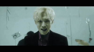 Man In Suit And Purple Shirt With Balloons In Dark Room GIF