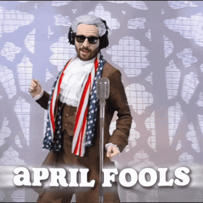 Man In Suit And Scarf At Microphone Saying April Fools GIF