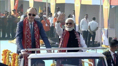 Man In Suit And Scarf Next To Bearded Man With Sunglasses GIF