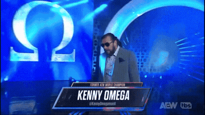 Man In Suit And Sunglasses At Kenny Omega Sign GIF