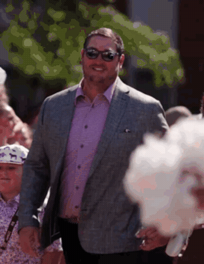 Man In Suit And Sunglasses Walking Before Crowd GIF