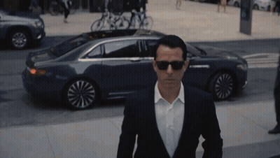 Man In Suit And Sunglasses Walking Past Car GIF
