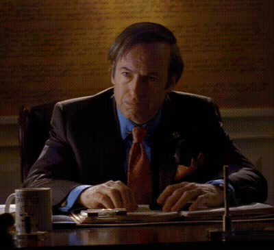 Man In Suit And Tie At Desk With Poof GIF