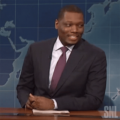 Man In Suit And Tie At Desk With SNL Logo GIF