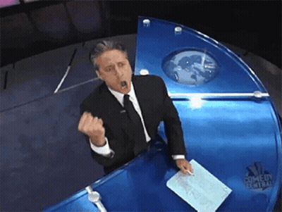 Man In Suit And Tie At NBC Comedy Central News Desk GIF