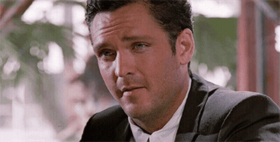 Man In Suit And Tie At Table Looking At Something GIF