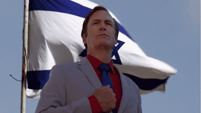 Man In Suit And Tie Before Blue And White Flag GIF