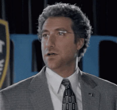 Man In Suit And Tie Before Blue Sign GIF