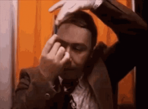 Man In Suit And Tie Covering Nose With Hands GIF
