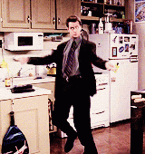Man In Suit And Tie Dancing In Kitchen In Front Of Refrigerator GIF