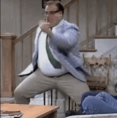 Man In Suit And Tie Dancing Next To Couch GIF