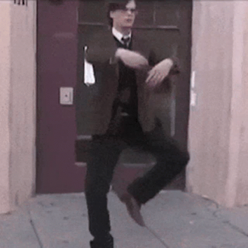 Man In Suit And Tie Dancing On One Leg GIF