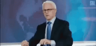 Man In Suit And Tie Facing Skull On Screen GIF