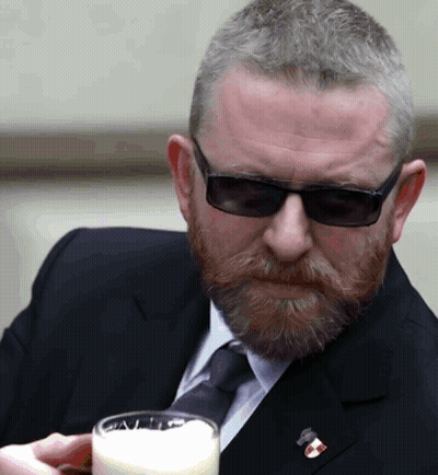 Man In Suit And Tie Holding Glass Of Milk GIF