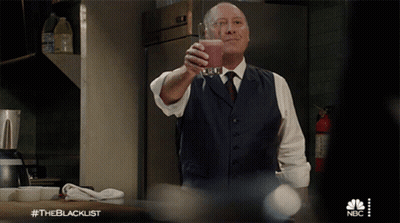 Man In Suit And Tie Holding Glass With NBC Logo GIF