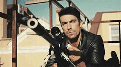 Man In Suit And Tie Holding Gun Saying The Hit Man Is Home GIF