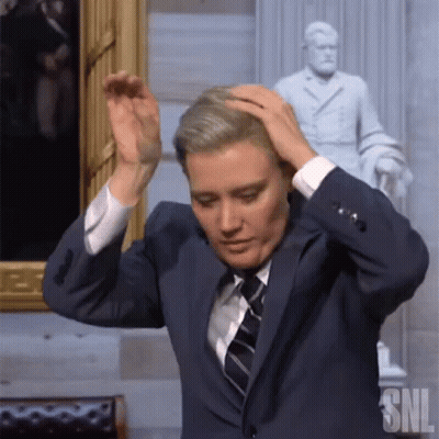 Man In Suit And Tie Holding Head Next To SNL Statue GIF