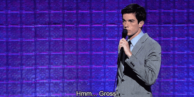 Man In Suit And Tie Holding Microphone Saying Hmm Gross GIF