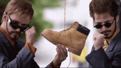 Man In Suit And Tie Holding Pair Of Boots GIF