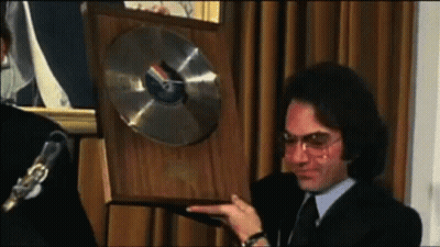 Man In Suit And Tie Holding Plaque With Record GIF