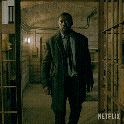 Man In Suit And Tie In Dark Room With Netflix Logo GIF