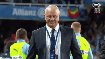 Man In Suit And Tie In Front Of Allianz Banner GIF