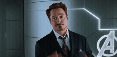 Man In Suit And Tie In Front Of Avengers Sign GIF