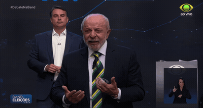 Man In Suit And Tie In Front Of Band Eleioes Sign GIF