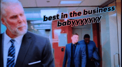 Man In Suit And Tie In Front Of Best In The Business Baby Sign GIF